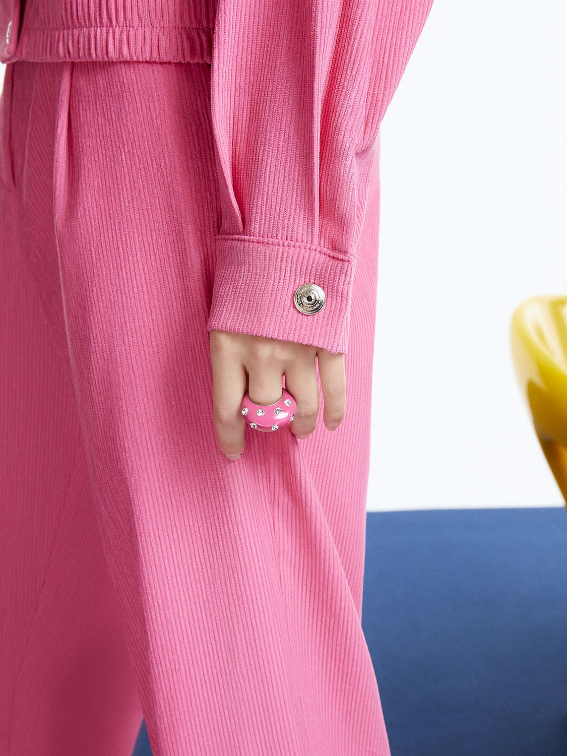 A pair of high-waisted corduroy slouchy pants in vibrant orange, pink, and blue colors, featuring pleat details and side pockets.