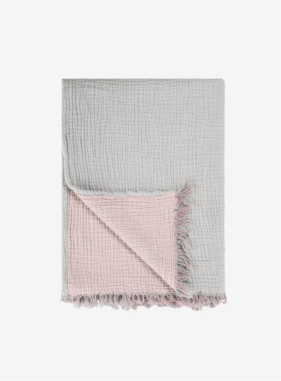 A cozy Cotton Throw Blanket in powder pink and gray, showcasing its double-sided design and soft texture, perfect for couch or beach use.