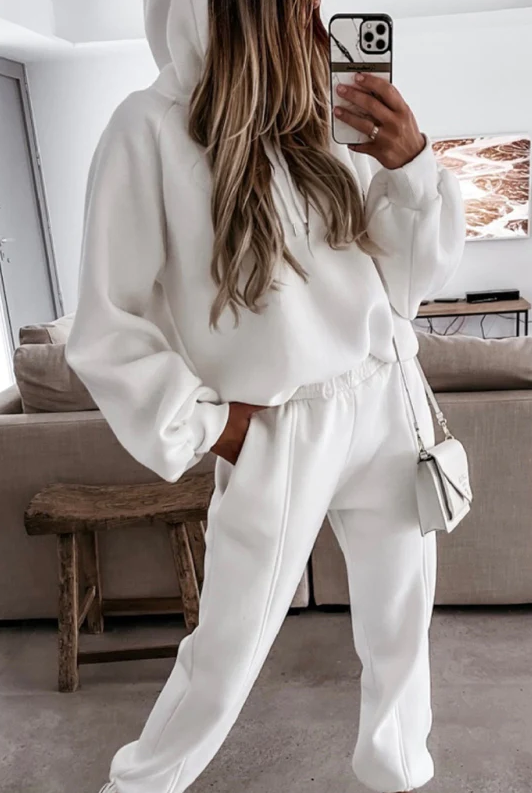 White cotton tracksuit set featuring a loose-fitting sweatshirt with a hoodie and long pants, made from soft and stretchy material.