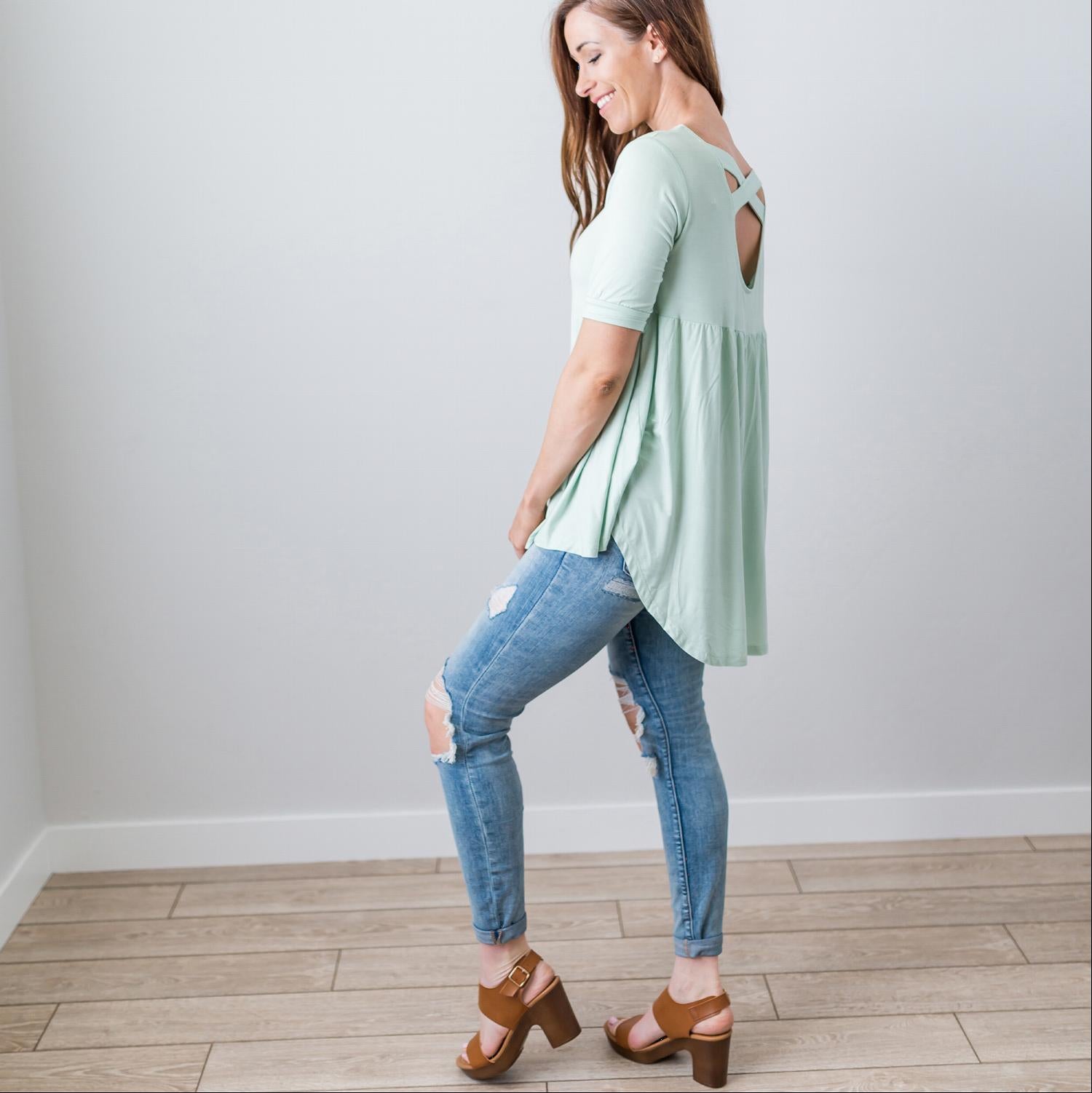 A stylish Criss Cross Back Hi-Low Scoop Hem Top in soft fabric, featuring three-quarter sleeves and a flattering fit, perfect for spring and summer wear.