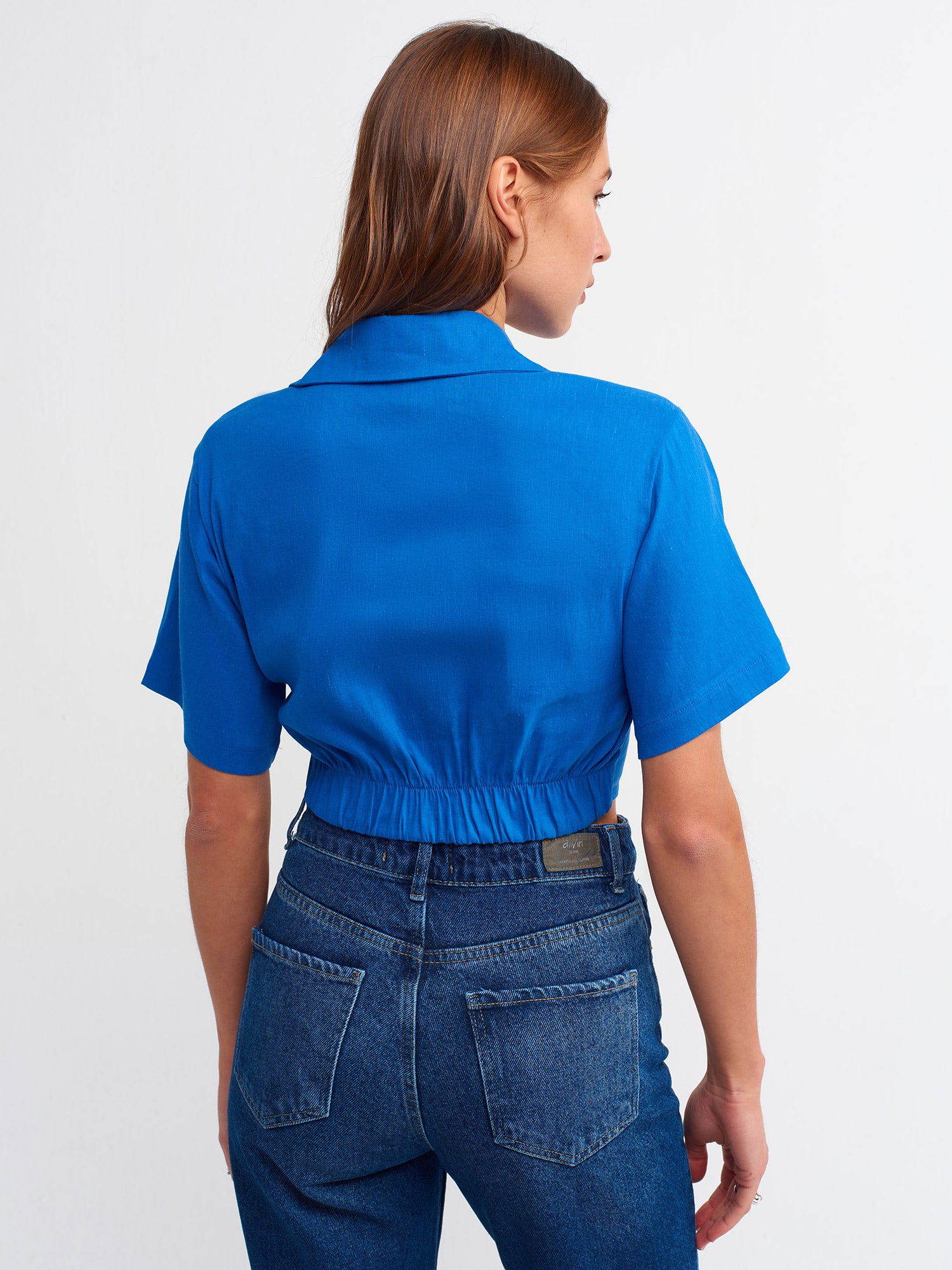 A stylish crop shirt made from a blend of linen, viscose, polyamide, and elastane, showcasing its trendy design and comfortable fit.