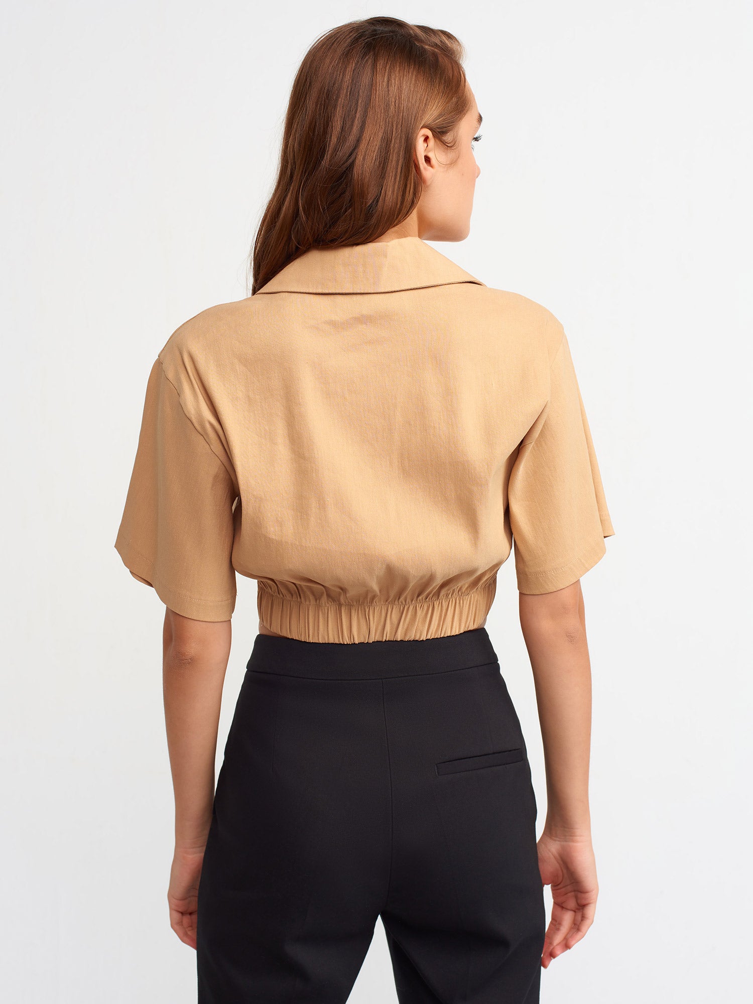 A stylish crop shirt made from a blend of linen, viscose, polyamide, and elastane, showcasing its trendy design and comfortable fit.