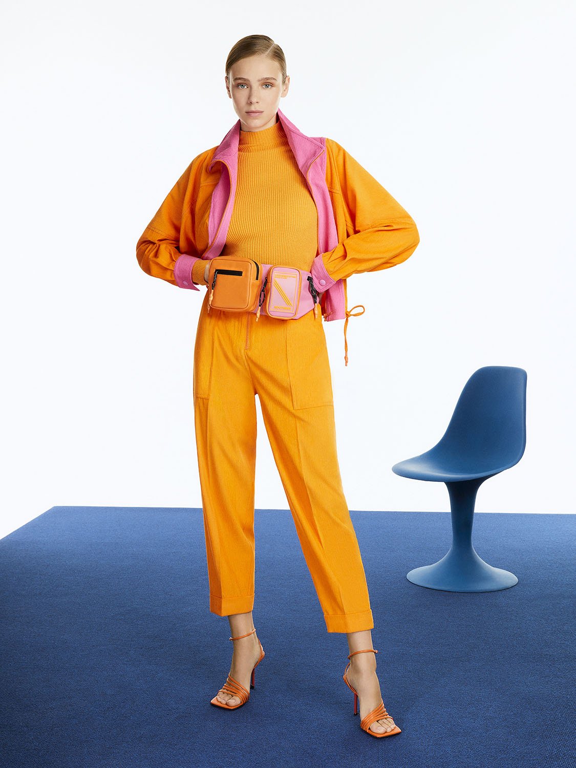 A pair of stylish cuffed corduroy pants in vibrant orange, pink, and blue colors, featuring a high-waisted design and elastic waistband.