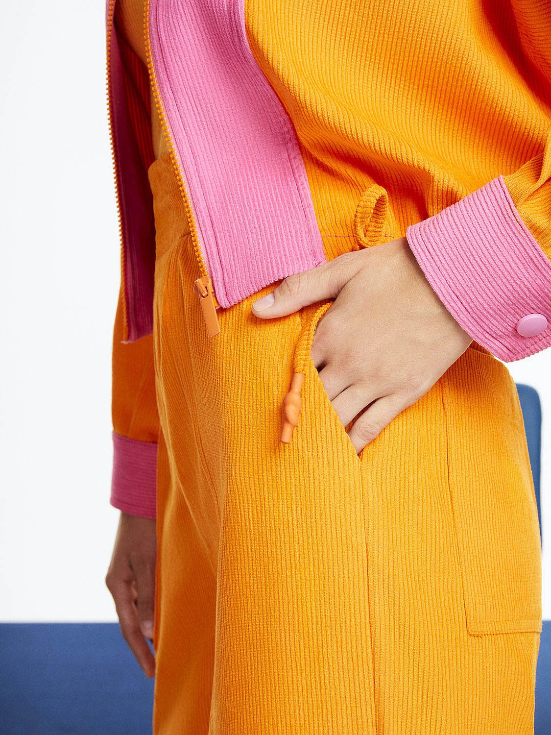 A pair of stylish cuffed corduroy pants in vibrant orange, pink, and blue colors, featuring a high-waisted design and elastic waistband.