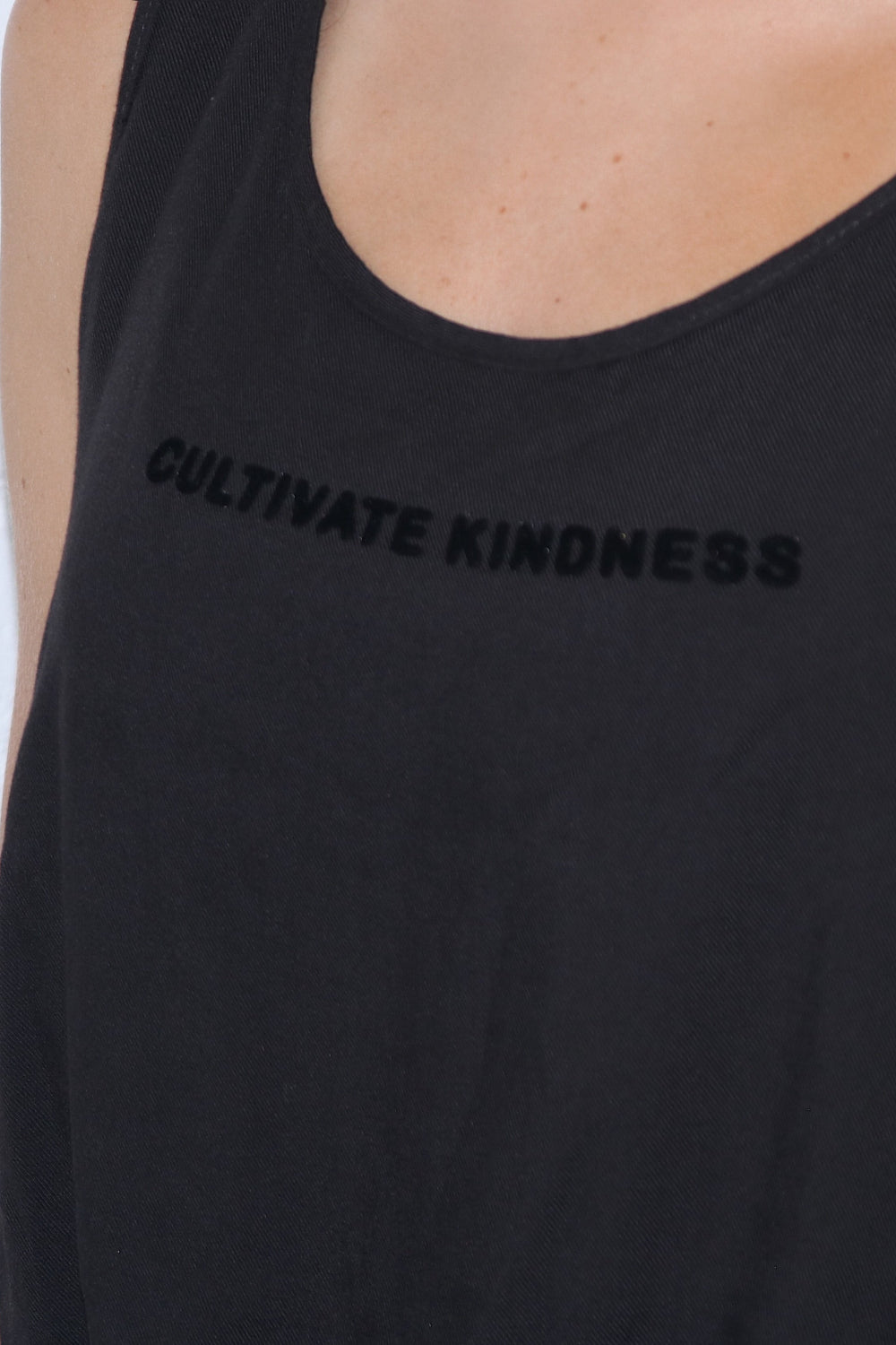 A stylish black cropped tank top with the phrase 'Cultivate Kindness' printed, showcasing a relaxed fit and lightweight fabric.