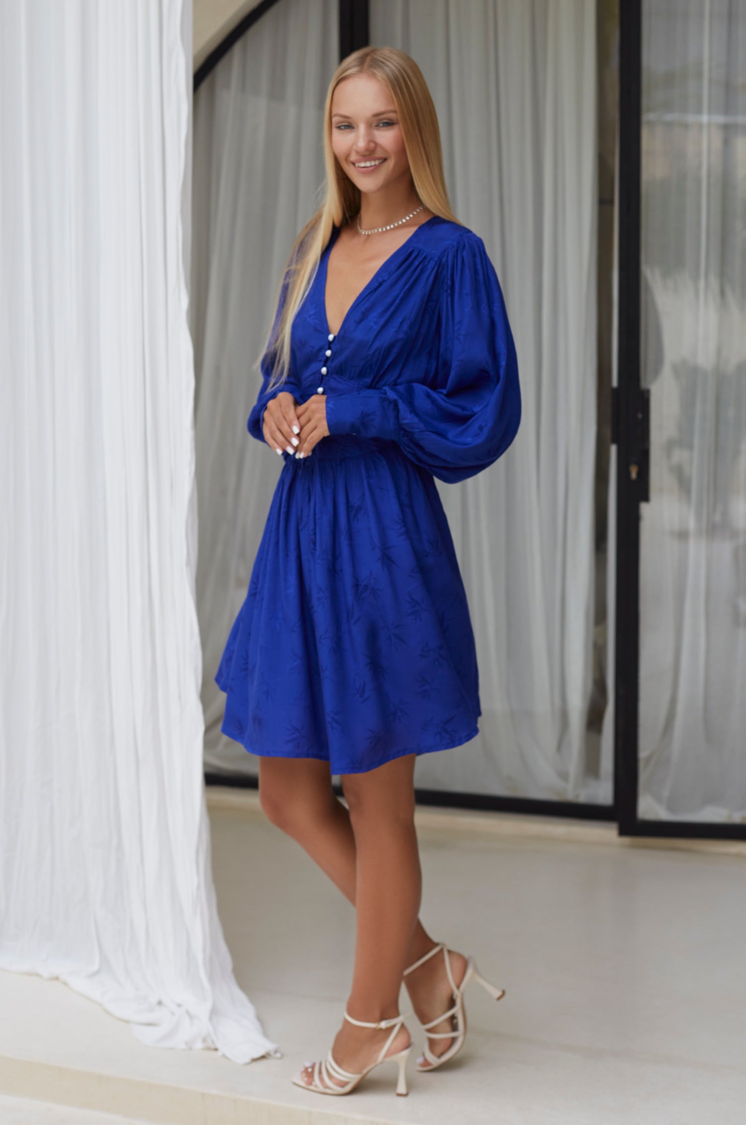 Daphne Floaty Long Sleeve Mini Dress featuring a romantic silhouette, voluminous sleeves, and pearl button details, made from soft organic cotton.