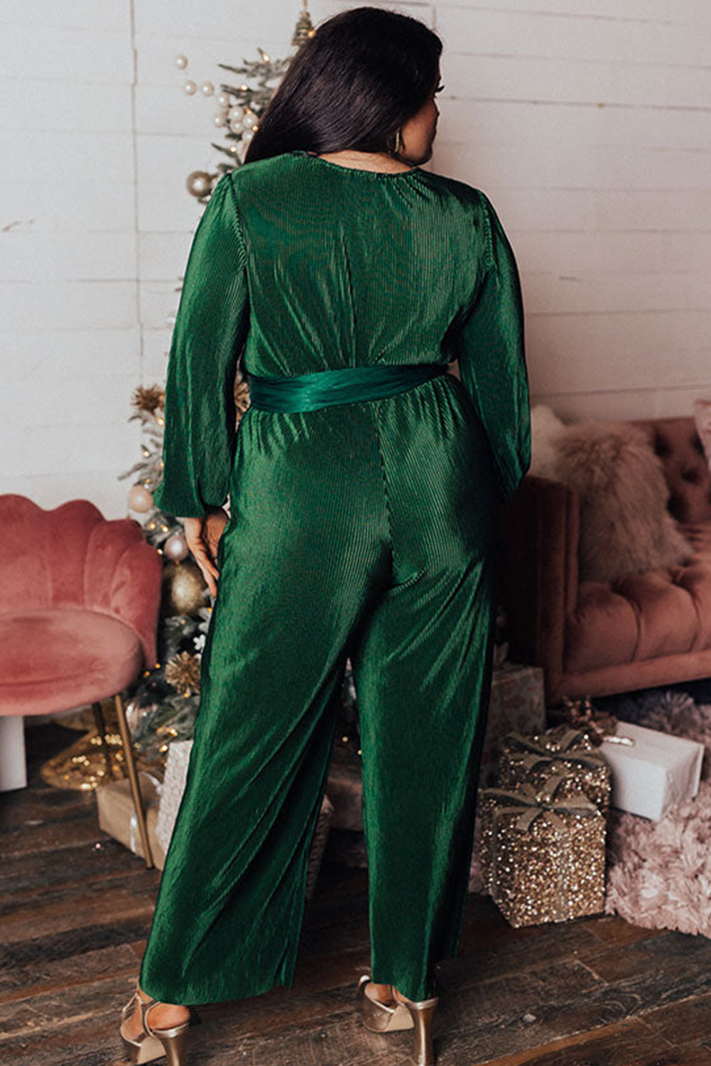 Dark green plus size pleated satin belted V neck jumpsuit displayed on a mannequin, showcasing its elegant design and wide-leg silhouette.