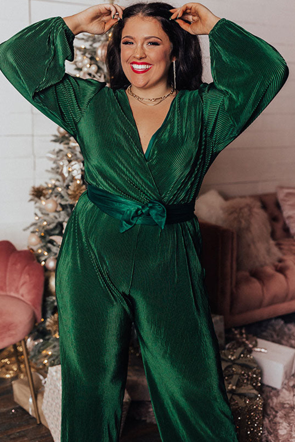 Dark green plus size pleated satin belted V neck jumpsuit displayed on a mannequin, showcasing its elegant design and wide-leg silhouette.