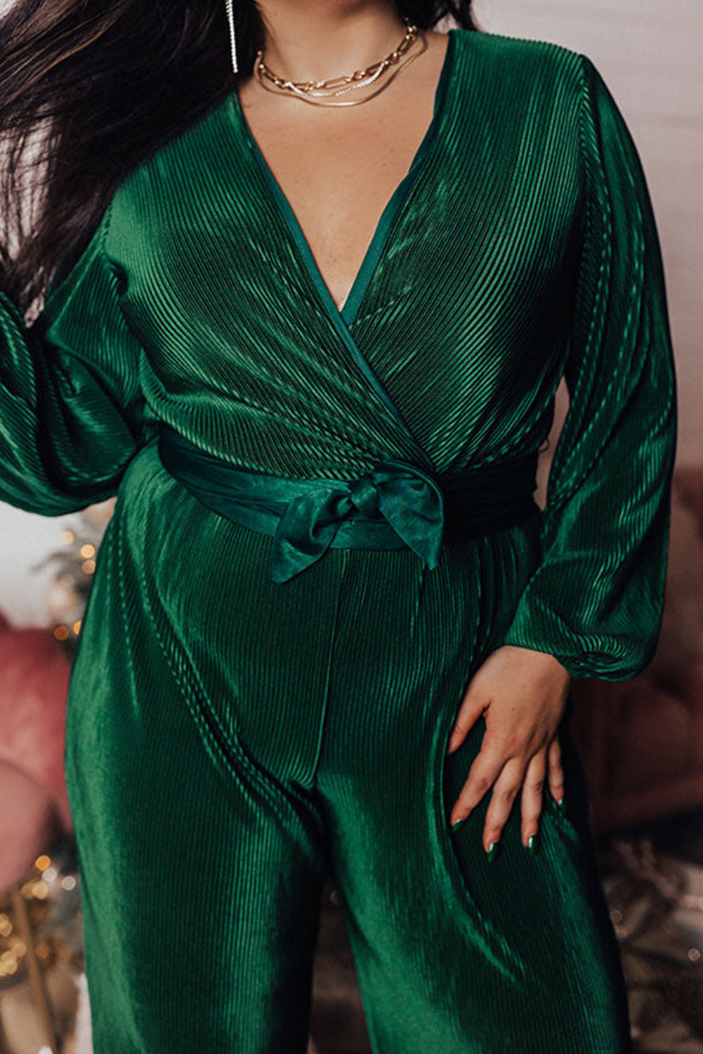 Dark green plus size pleated satin belted V neck jumpsuit displayed on a mannequin, showcasing its elegant design and wide-leg silhouette.