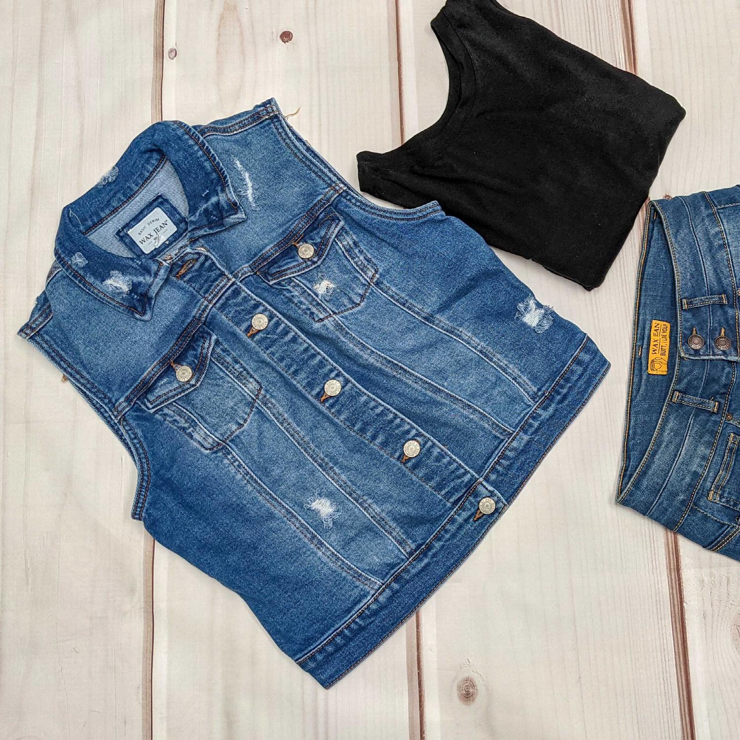 A stylish destructed denim vest featuring a rugged finish, button-up front, and chest pockets, perfect for layering over various outfits.