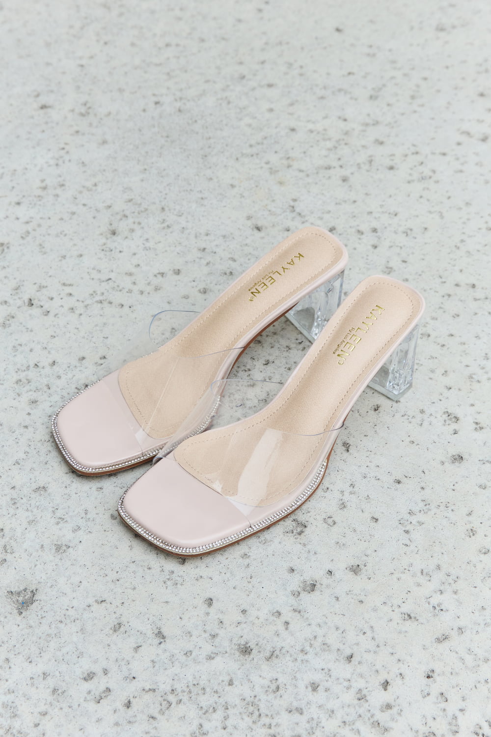 DDK Make Myself Clear Mule Block Heels featuring a transparent strap and block heel in a nude color.