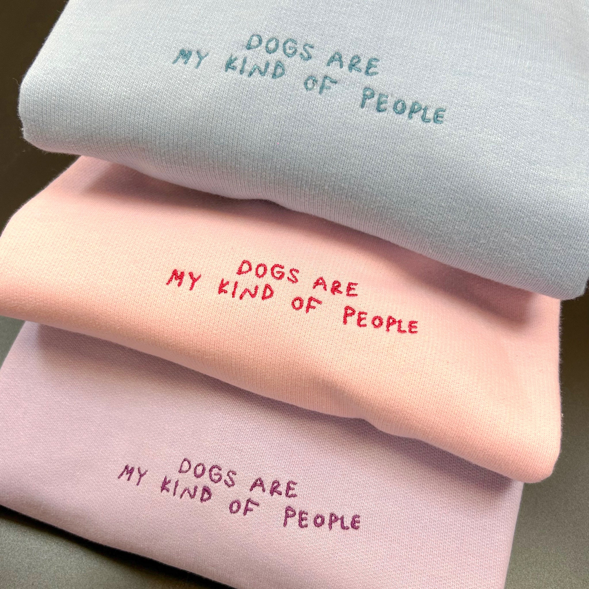 A cozy sweatshirt featuring the phrase 'Dogs Are My People' in pastel colors, perfect for dog lovers.