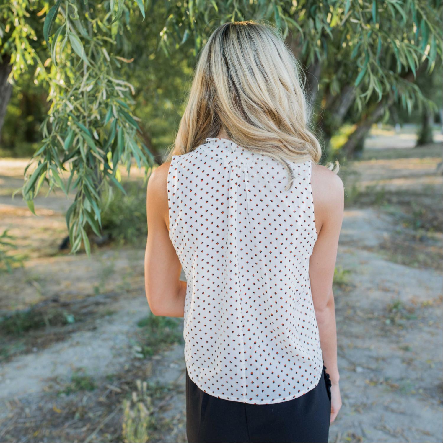 A stylish dot print sleeveless top in silk, featuring a partial button-down design, perfect for summer workwear.