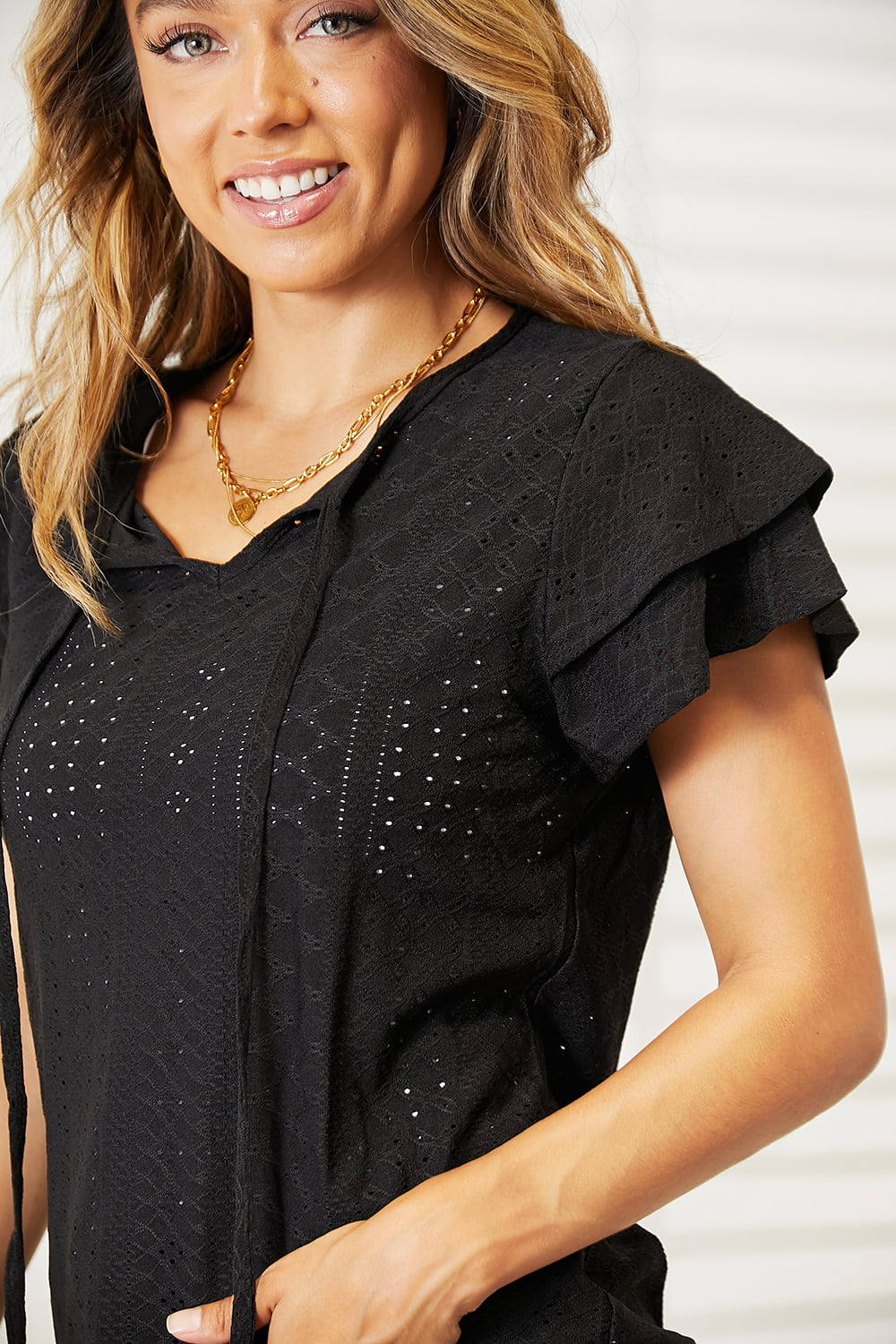 A stylish Double Take Eyelet Tie-Neck Flutter Sleeve Blouse featuring intricate eyelet design and flutter sleeves, perfect for any occasion.