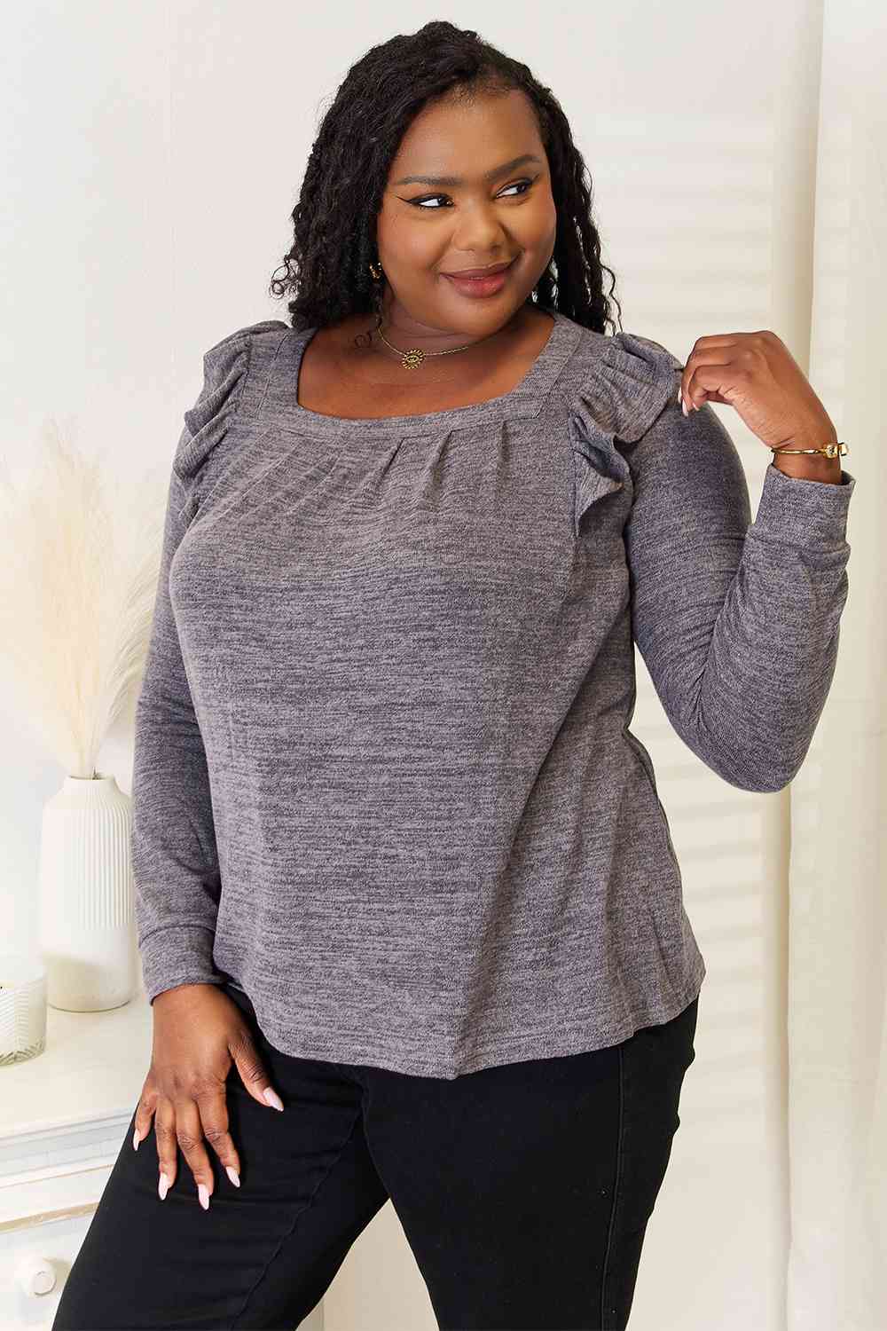 A stylish woman wearing a Double Take Square Neck Ruffle Shoulder Long Sleeve T-Shirt, showcasing its elegant square neckline and ruffle shoulder details.