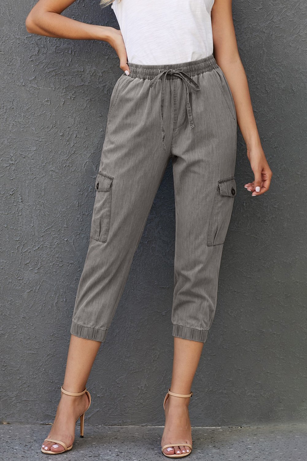 A pair of light wash denim joggers featuring cargo pockets, elastic drawstring waist, and banded ankles, perfect for casual wear.