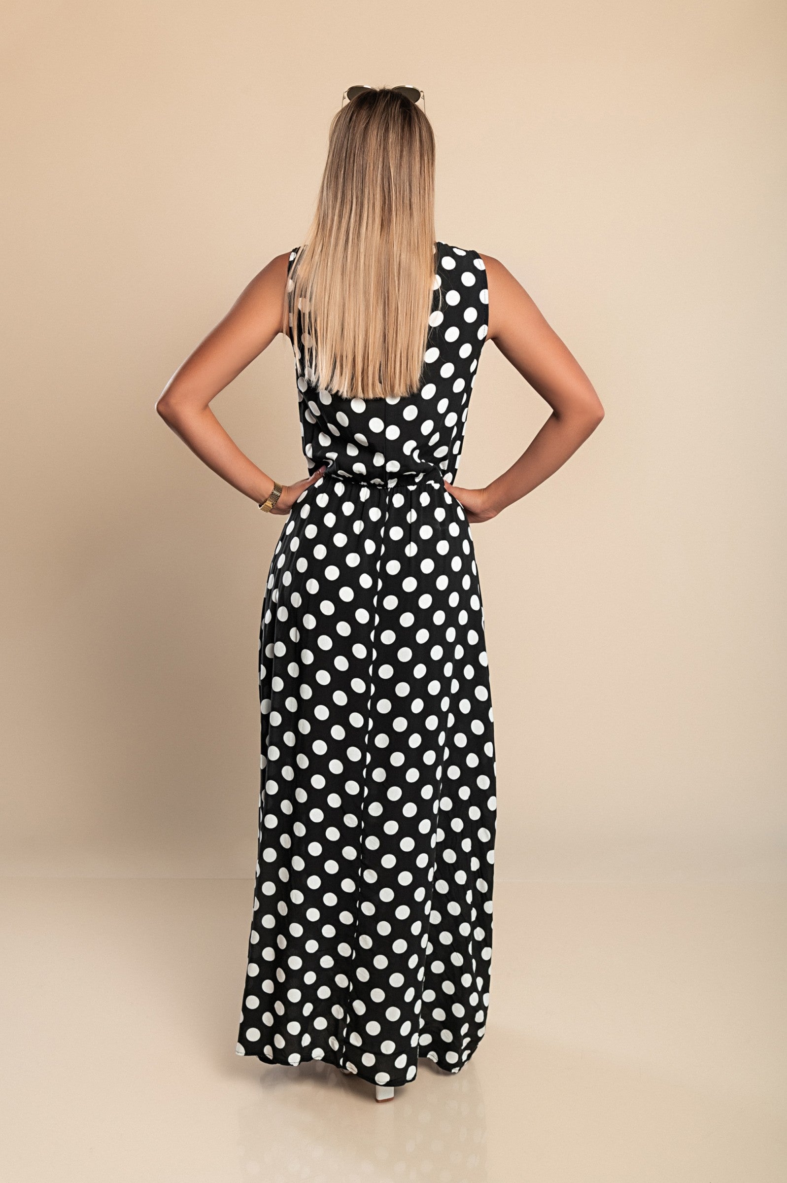 A stylish black sleeveless dress with a flowy skirt, featuring a back button closure and an elastic waist, made from 100% viscose.