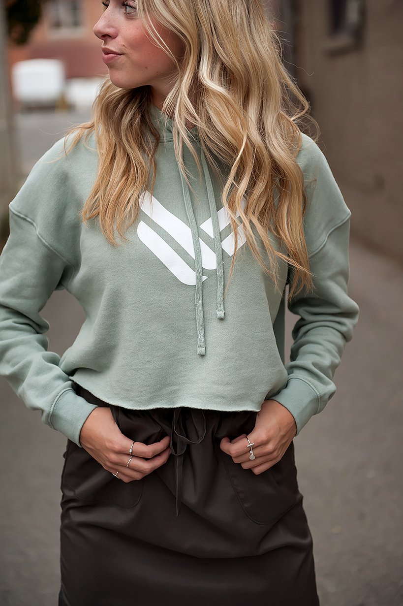 A lightweight sage green cropped hoodie featuring an adjustable hood and raw hem, perfect for casual wear.