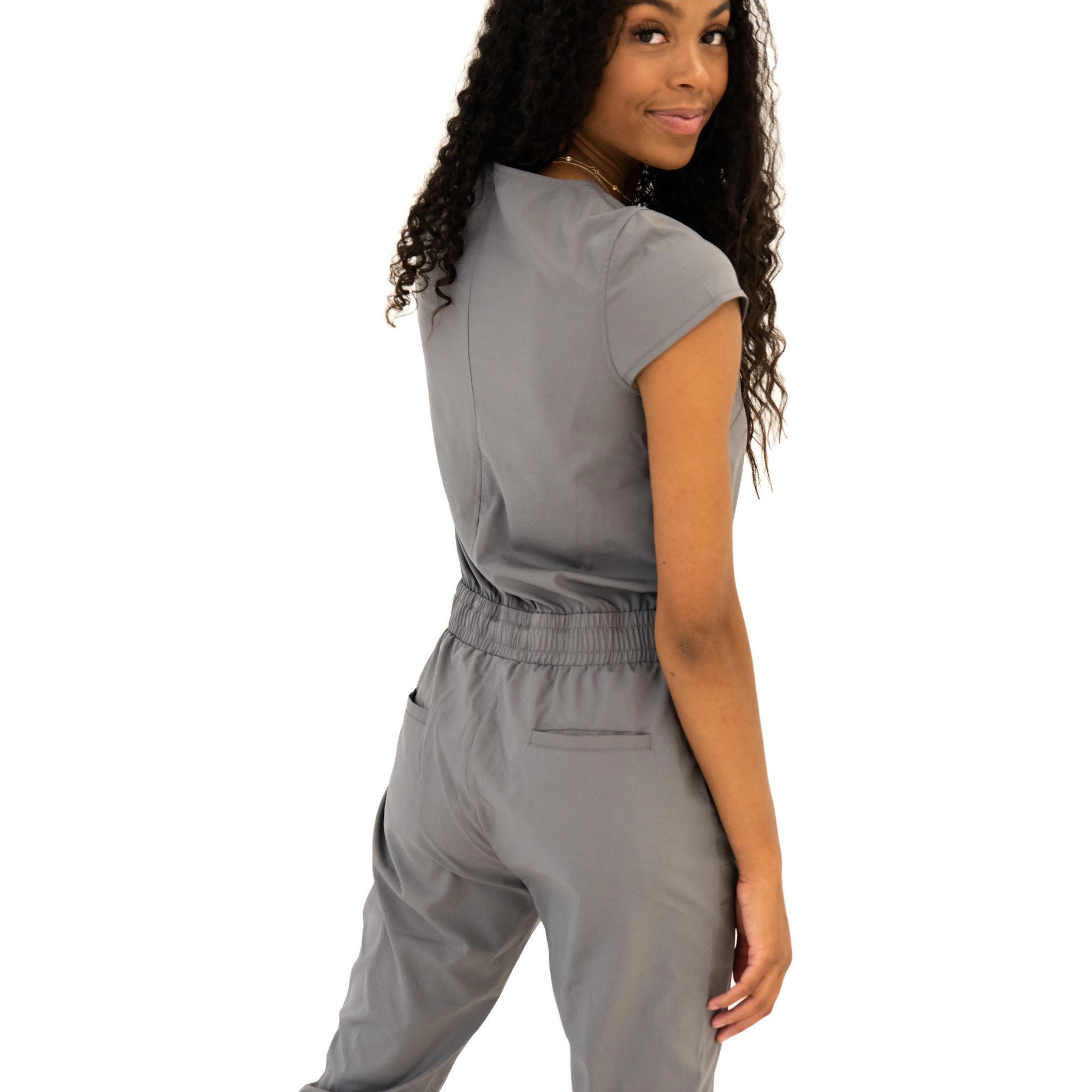 DT UNITY Jumpsuit in Cement featuring cap sleeves, adjustable tie waist, and pockets, displayed on a model.