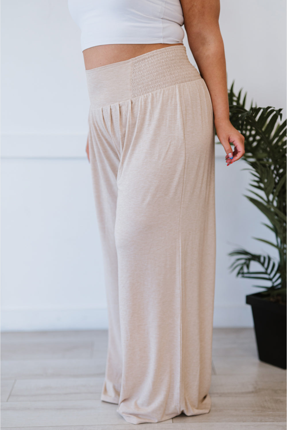 A pair of beige Easy Breezy Palazzo Pants featuring a wide leg and smocked waistband, styled with a crop top and heels.