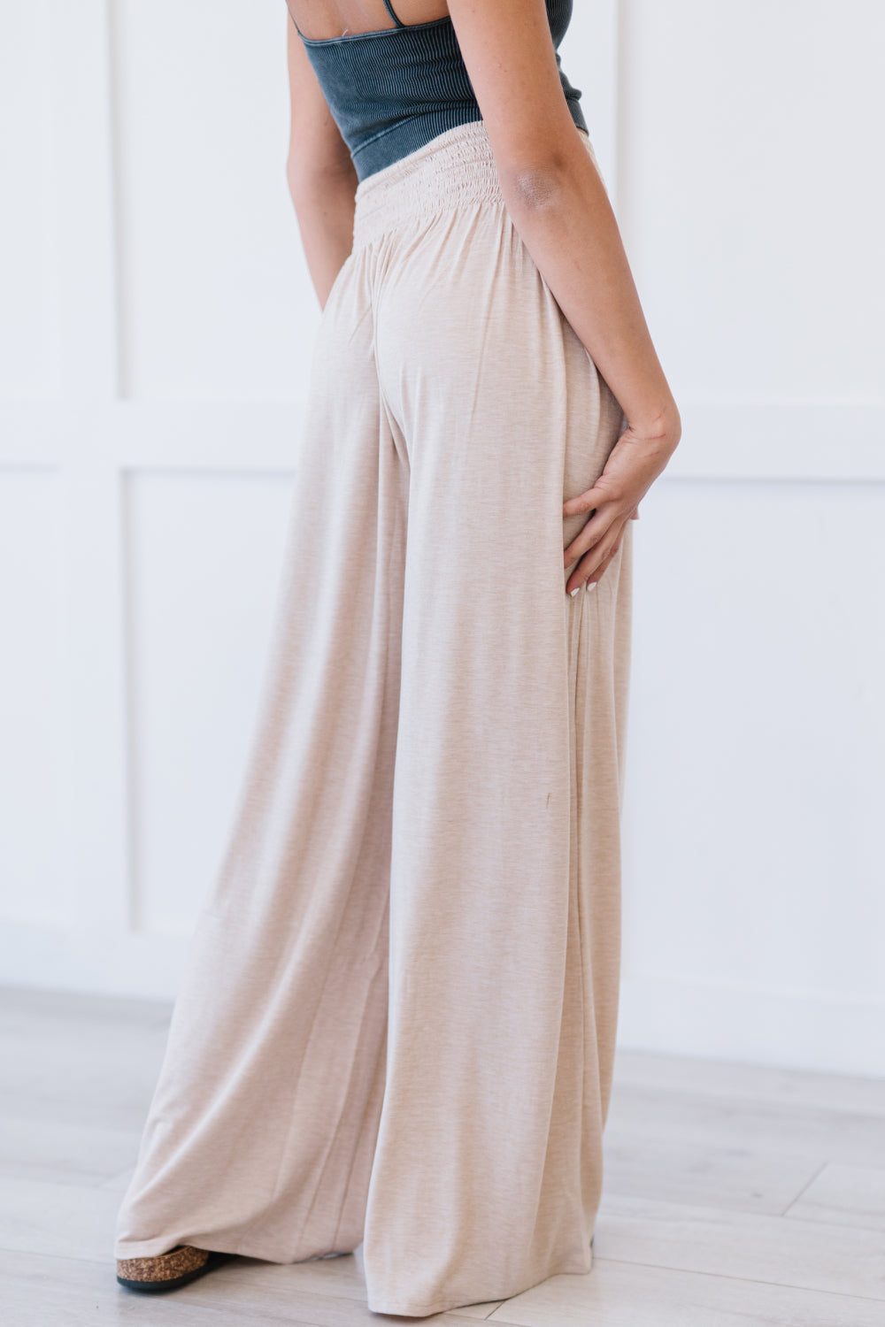 A pair of beige Easy Breezy Palazzo Pants featuring a wide leg and smocked waistband, styled with a crop top and heels.