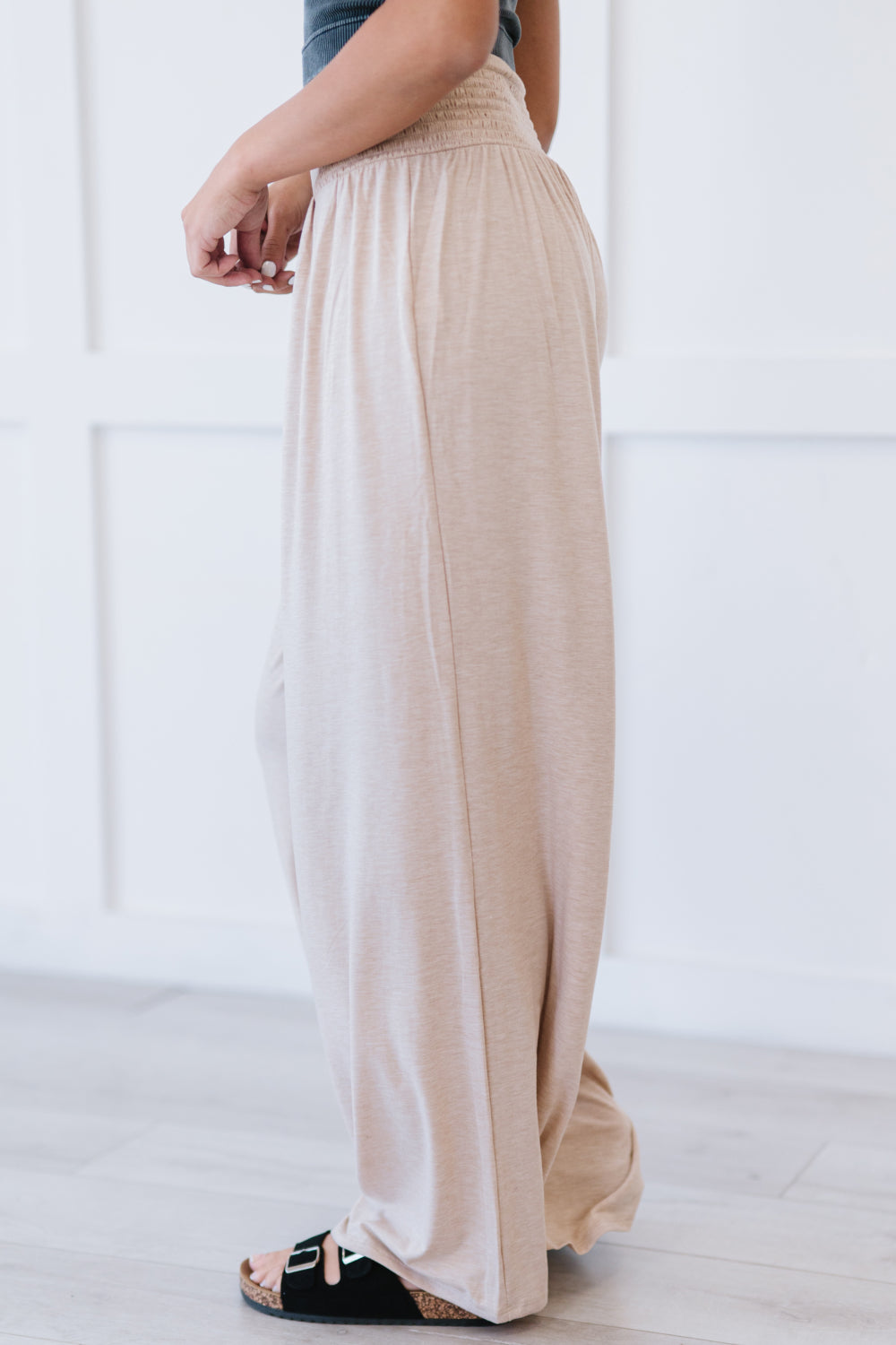 A pair of beige Easy Breezy Palazzo Pants featuring a wide leg and smocked waistband, styled with a crop top and heels.