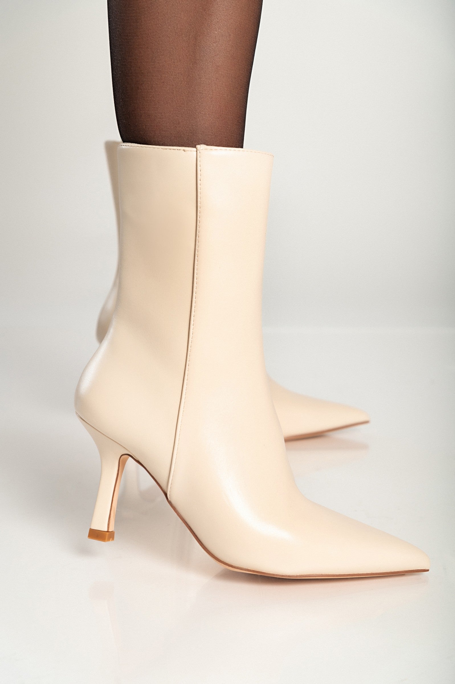 Elegant beige ankle boots with a pointed toe and thin heel, featuring an inside zipper closure for easy wear.