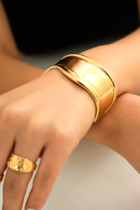 Elegant wide bracelet in gold color, made from metal alloy, showcasing a stylish design.