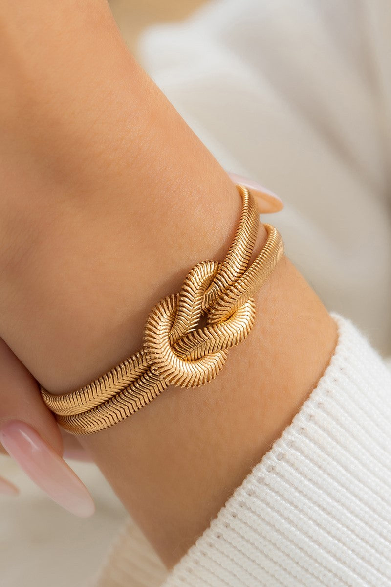 Elegant gold color bracelet featuring a decorative knot and metal hook closure, designed with multiple chains for a stylish look.