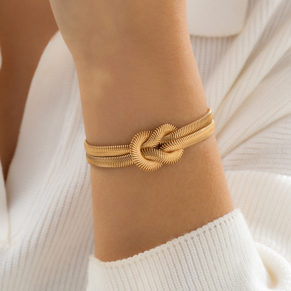 Elegant gold color bracelet featuring a decorative knot and metal hook closure, designed with multiple chains for a stylish look.