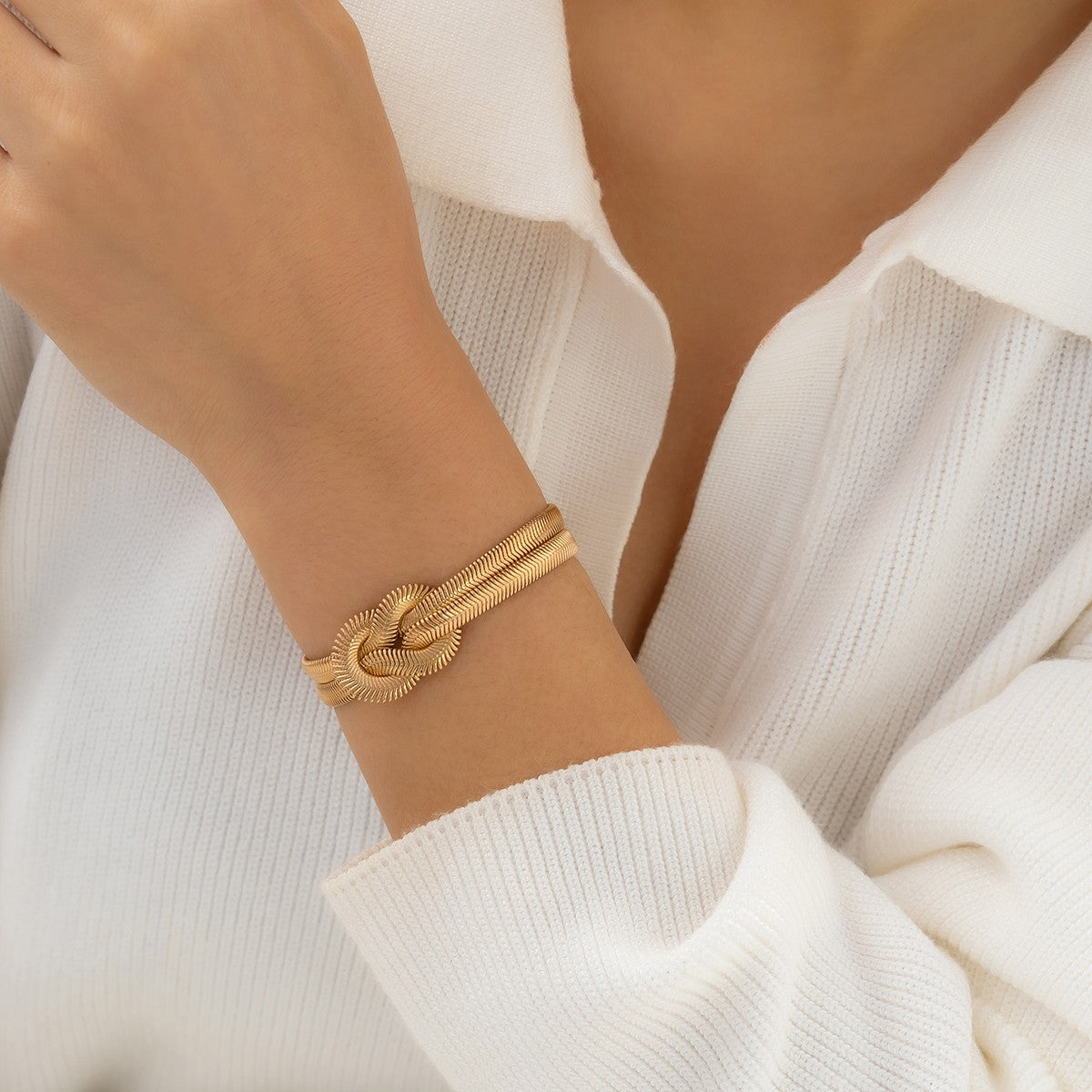 Elegant gold color bracelet featuring a decorative knot and metal hook closure, designed with multiple chains for a stylish look.