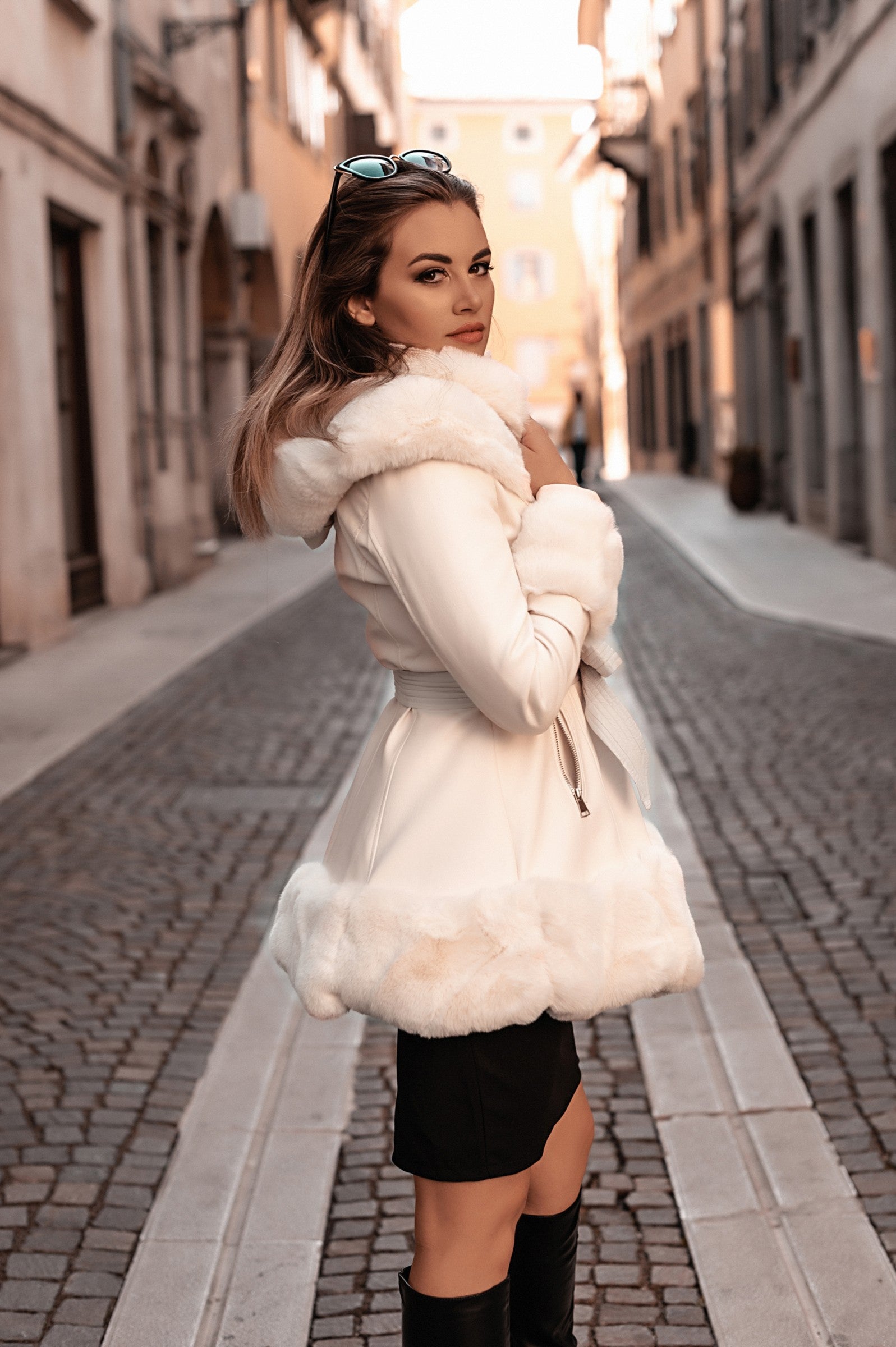 Elegant white coat with faux fur hood and details, featuring a full zip closure and front pockets.