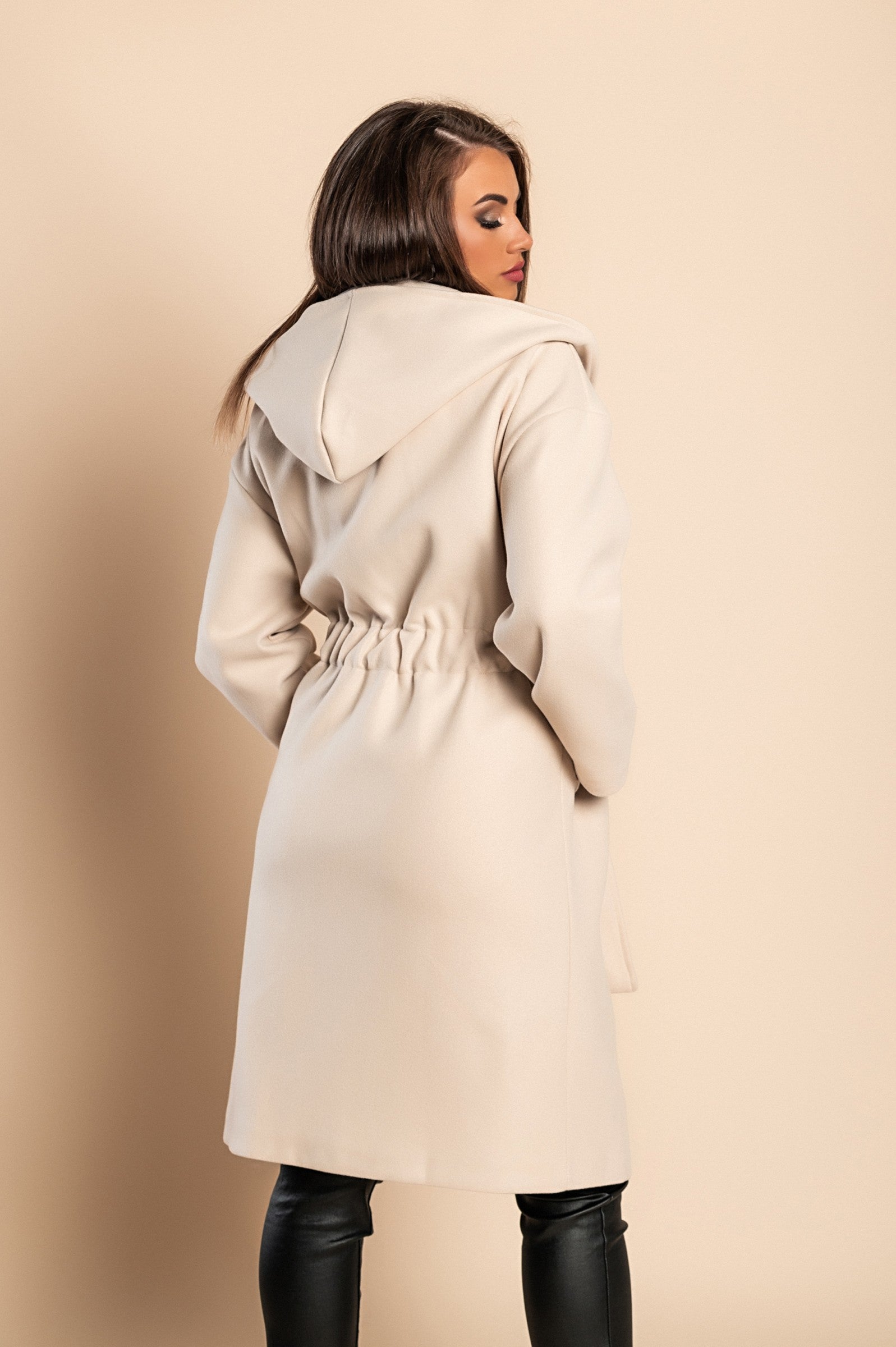 Elegant beige coat with hood, featuring long sleeves, elasticated waist, and decorative belt, perfect for stylish warmth.