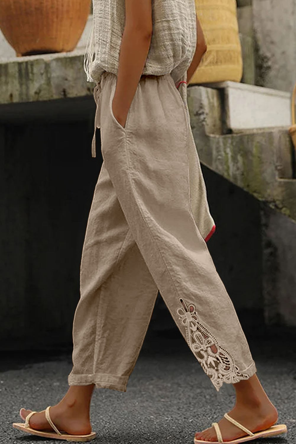 Elegant beige cotton trousers with lace detailing, featuring an elastic and drawstring waist, designed for comfort and style.