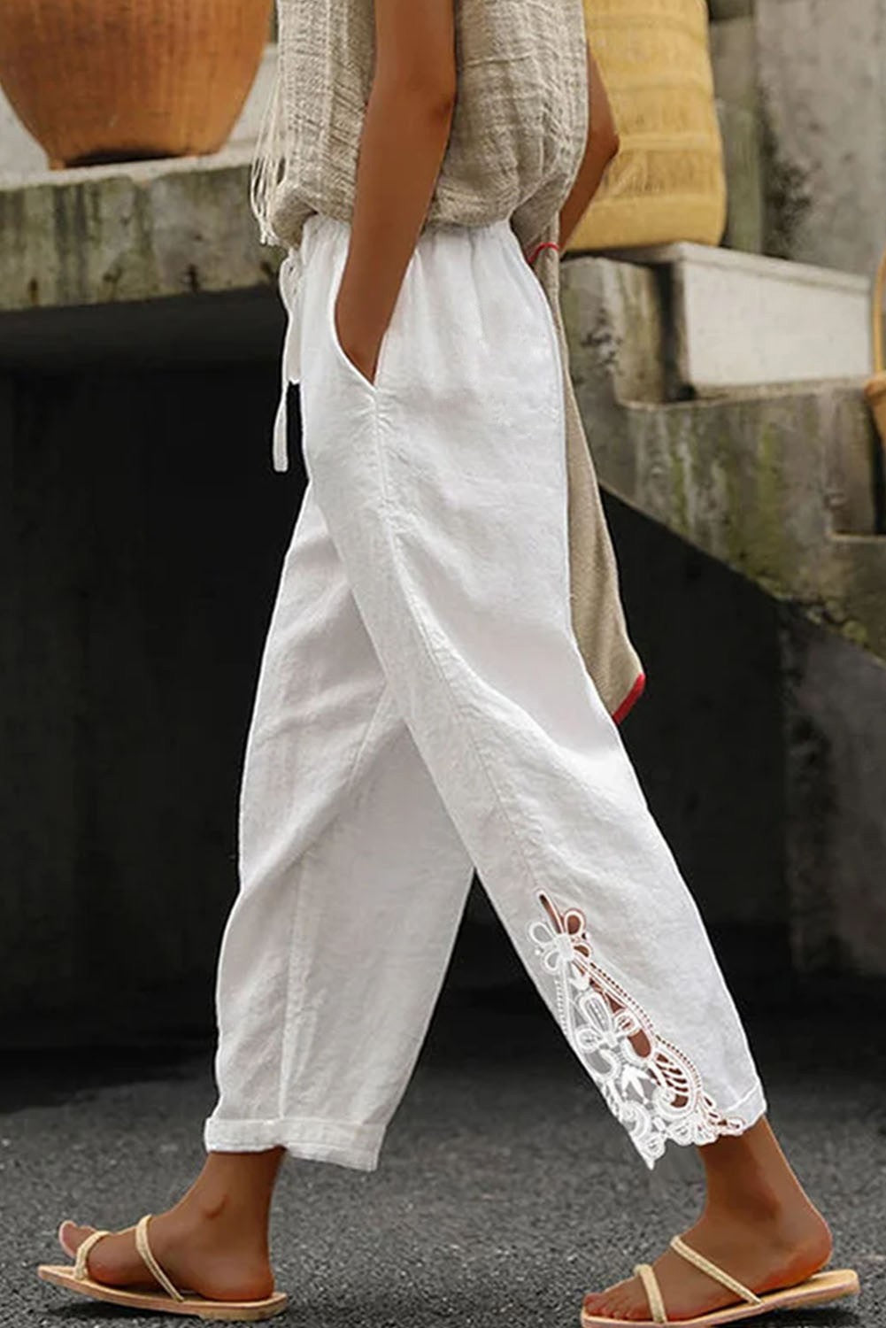 Elegant white cotton trousers with lace detailing and a drawstring waist, perfect for stylish comfort.