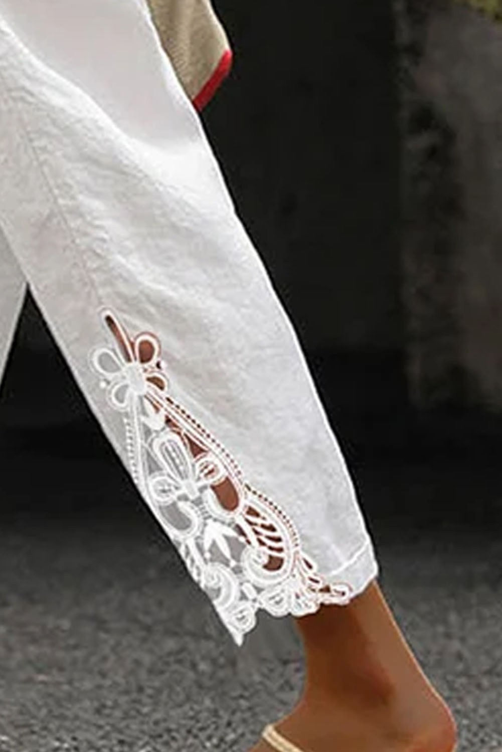 Elegant white cotton trousers with lace detailing and a drawstring waist, showcasing a stylish 7/8 length design.