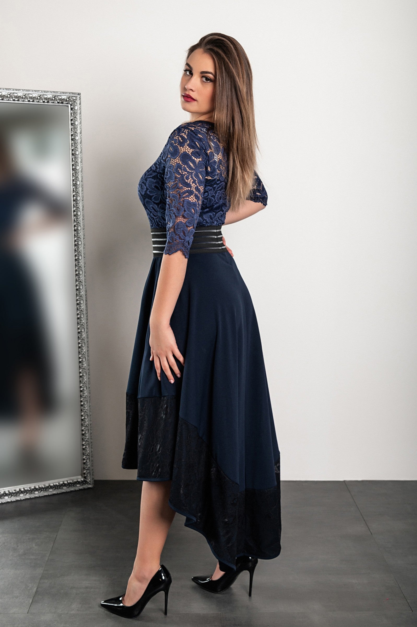 Elegant dark blue lace dress Bianca with asymmetrical design and sheer 3/4 sleeves, featuring a tight waist and lace detailing.