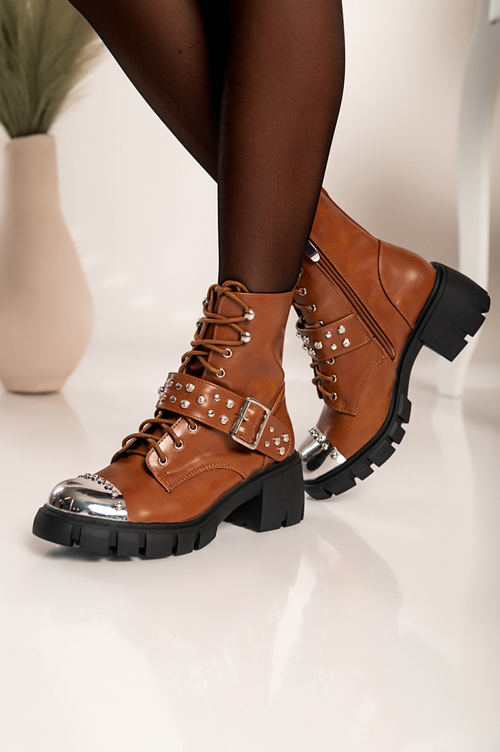 Elegant brown heeled ankle boots Coria with round toe, metal cap detail, and bows, showcasing high-quality artificial leather.