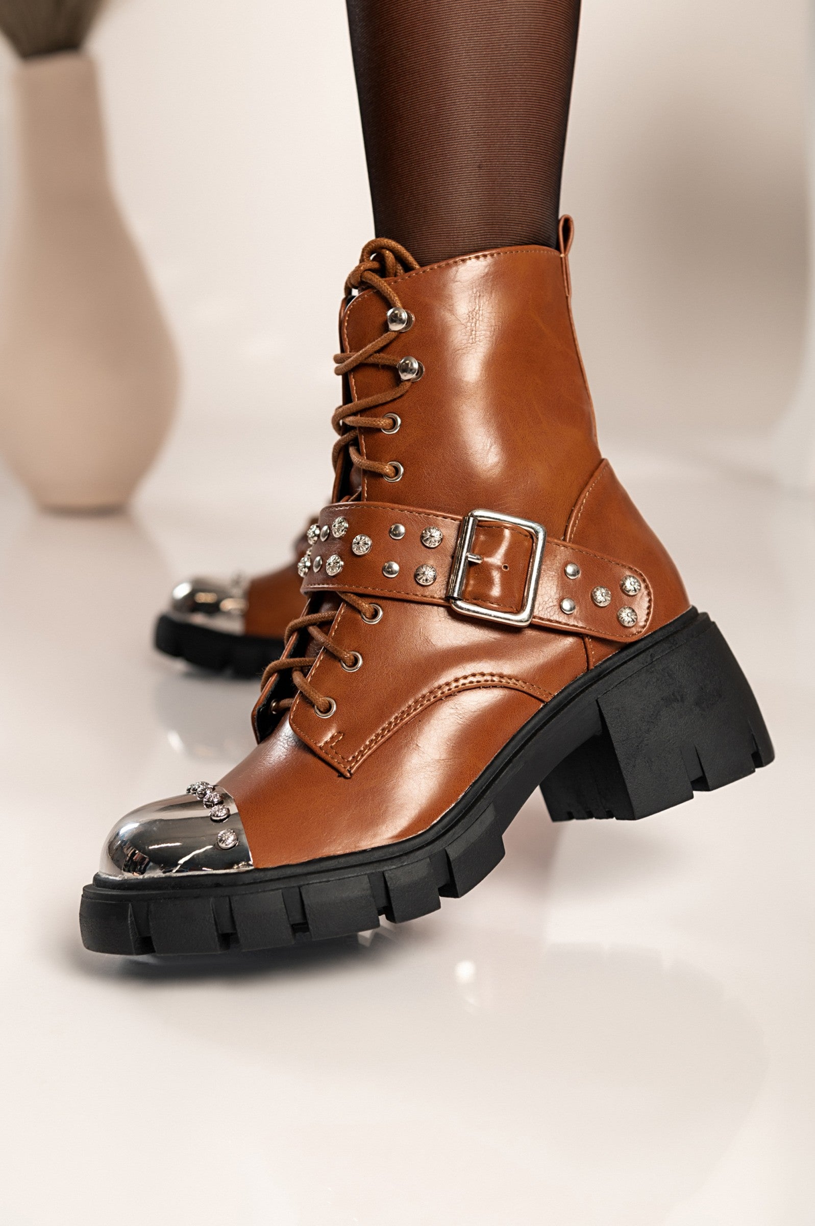 Elegant brown heeled ankle boots Coria with round toe, metal cap detail, and bows, showcasing high-quality artificial leather.