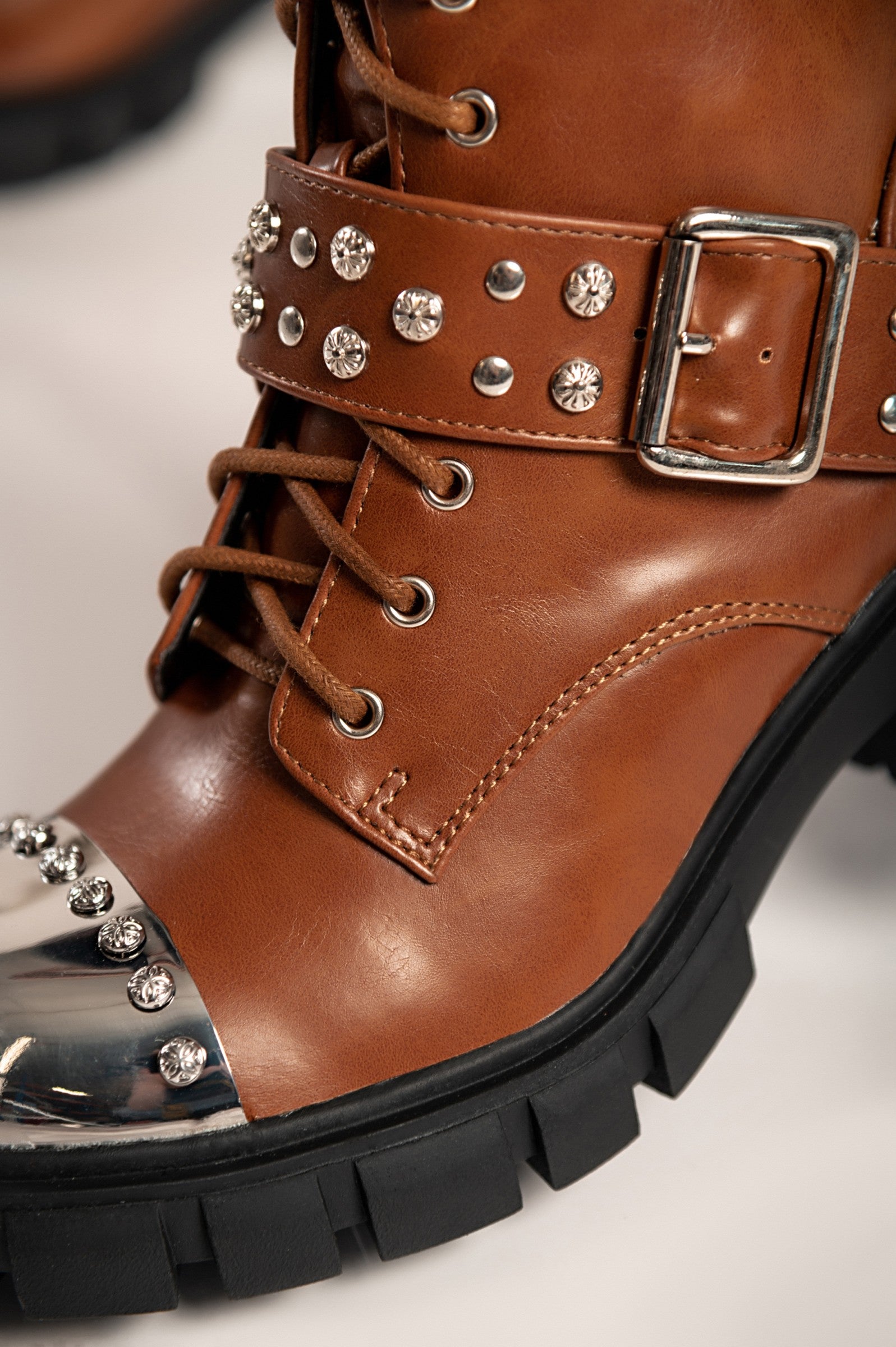 Elegant brown heeled ankle boots Coria with round toe, metal cap detail, and bows, showcasing high-quality artificial leather.