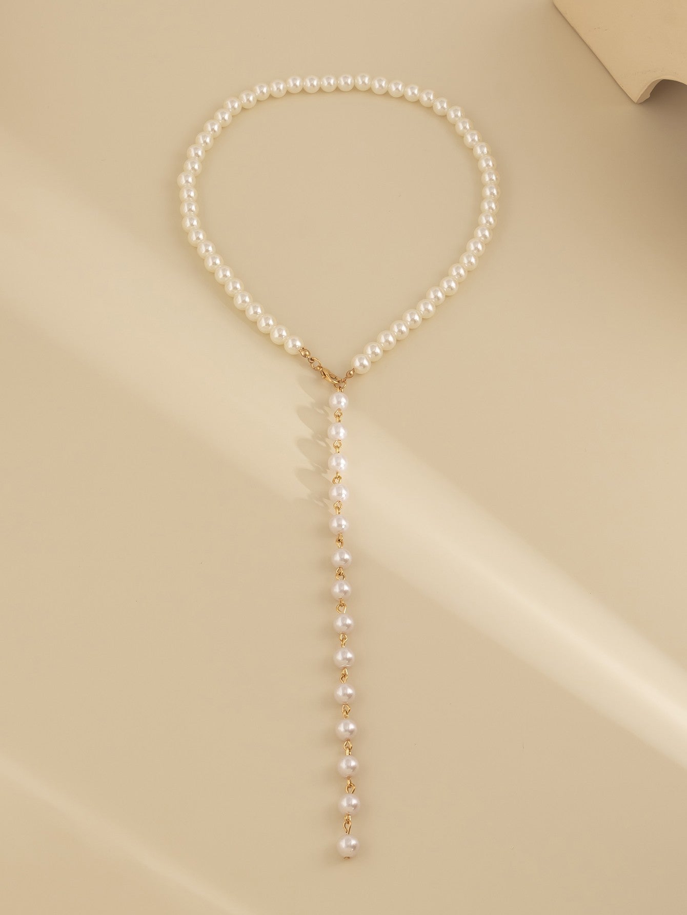 Elegant gold-colored imitation pearl necklace with a lobster clasp closure, showcasing a sophisticated design.