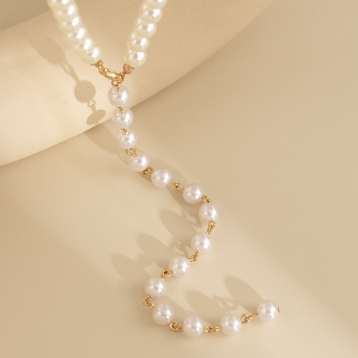 Elegant gold-colored imitation pearl necklace with a lobster clasp closure, showcasing a sophisticated design.