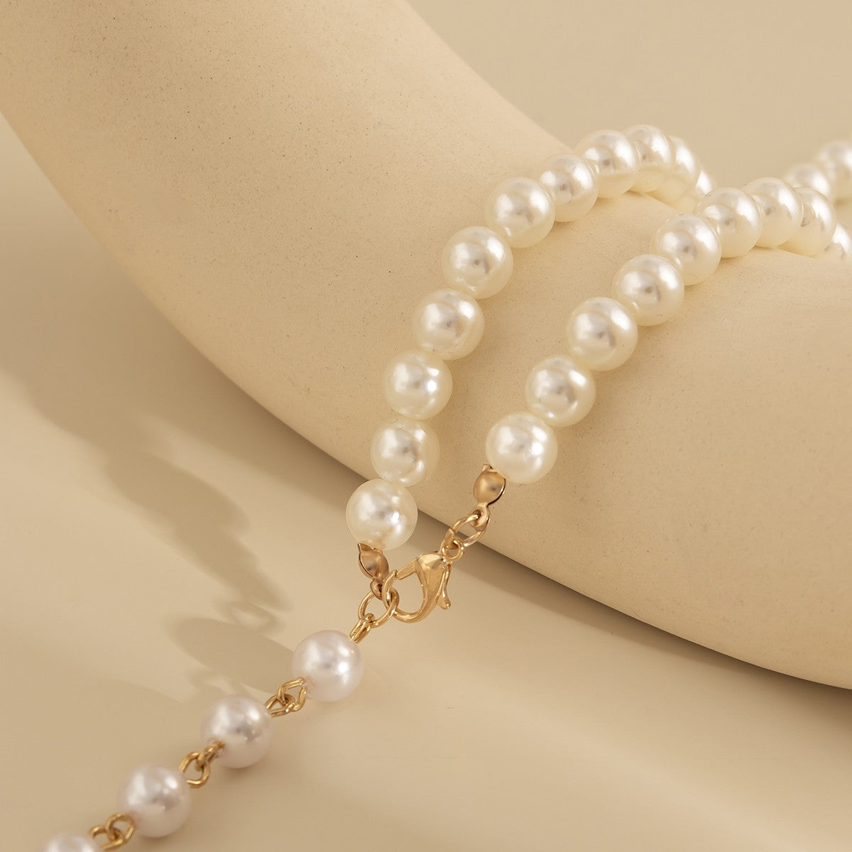 Elegant gold-colored imitation pearl necklace with a lobster clasp closure, showcasing a sophisticated design.