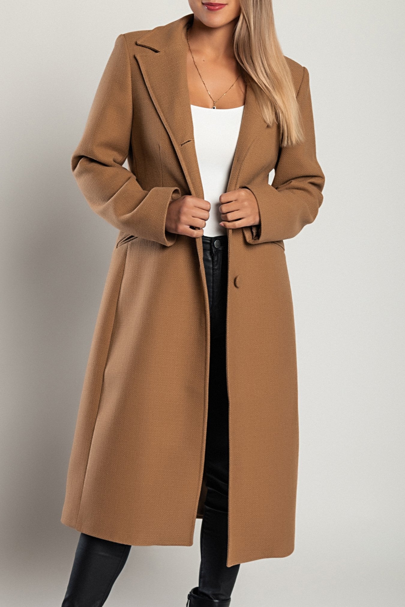 Elegant long coat in camel color with classic collar and button closure, featuring side pockets and long sleeves.