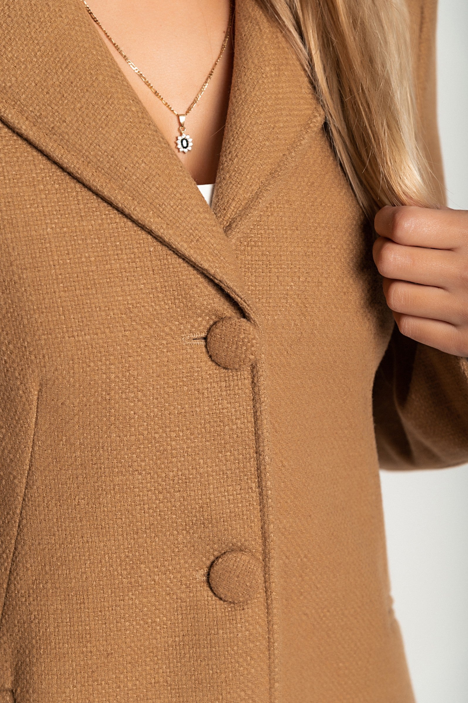 Elegant long coat in camel color with classic collar and button closure, featuring side pockets and long sleeves.