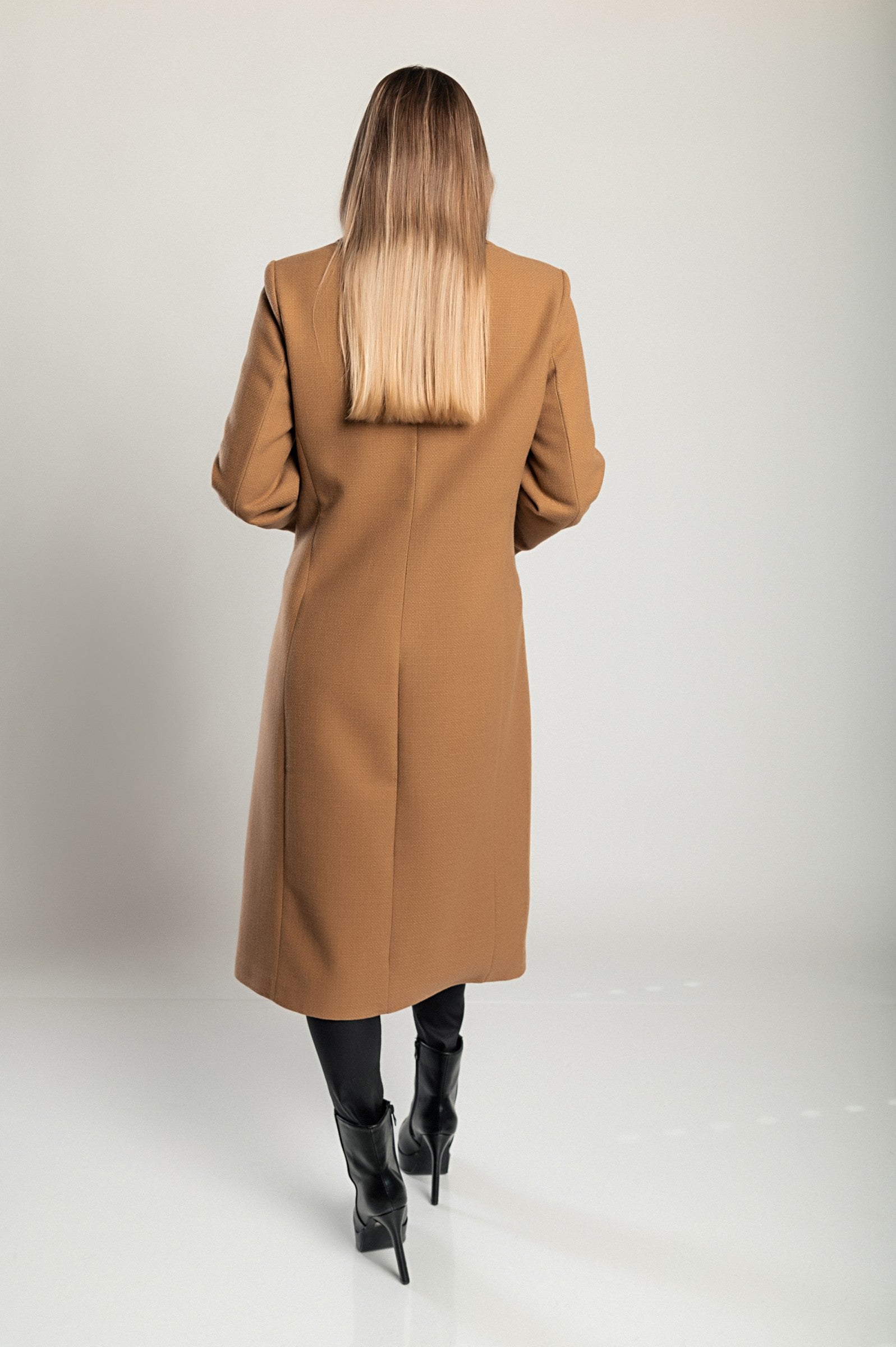 Elegant long coat in camel color with classic collar and button closure, featuring side pockets and long sleeves.