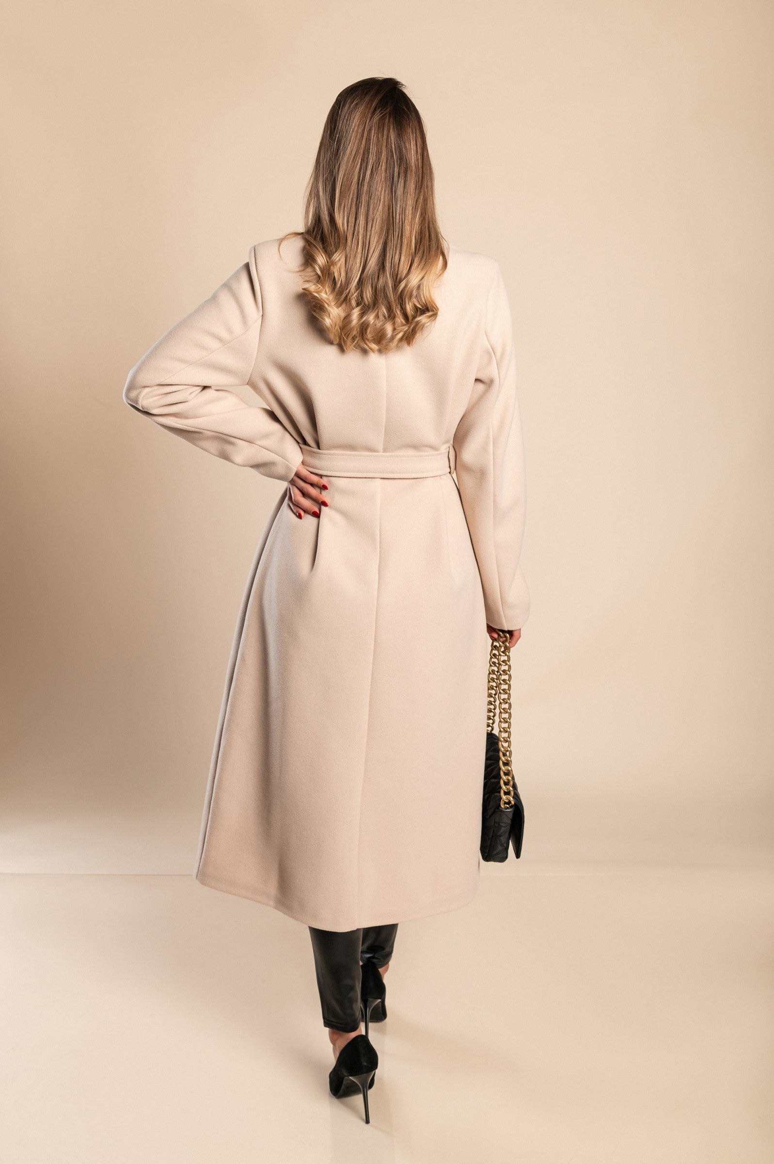 Elegant long beige coat with buttons, featuring a classic collar and decorative belt, made from high-quality soft fabric.