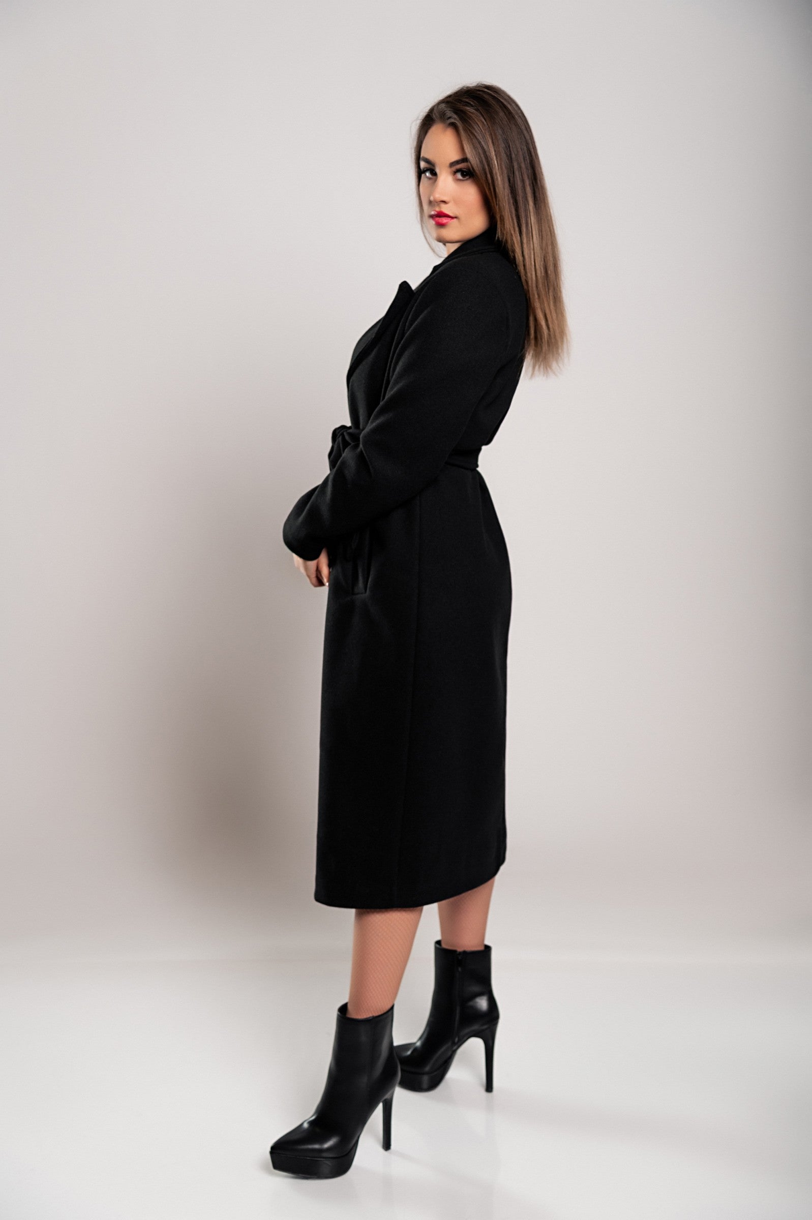 Elegant black long coat with buttons and decorative belt, showcasing classic collar and long sleeves.