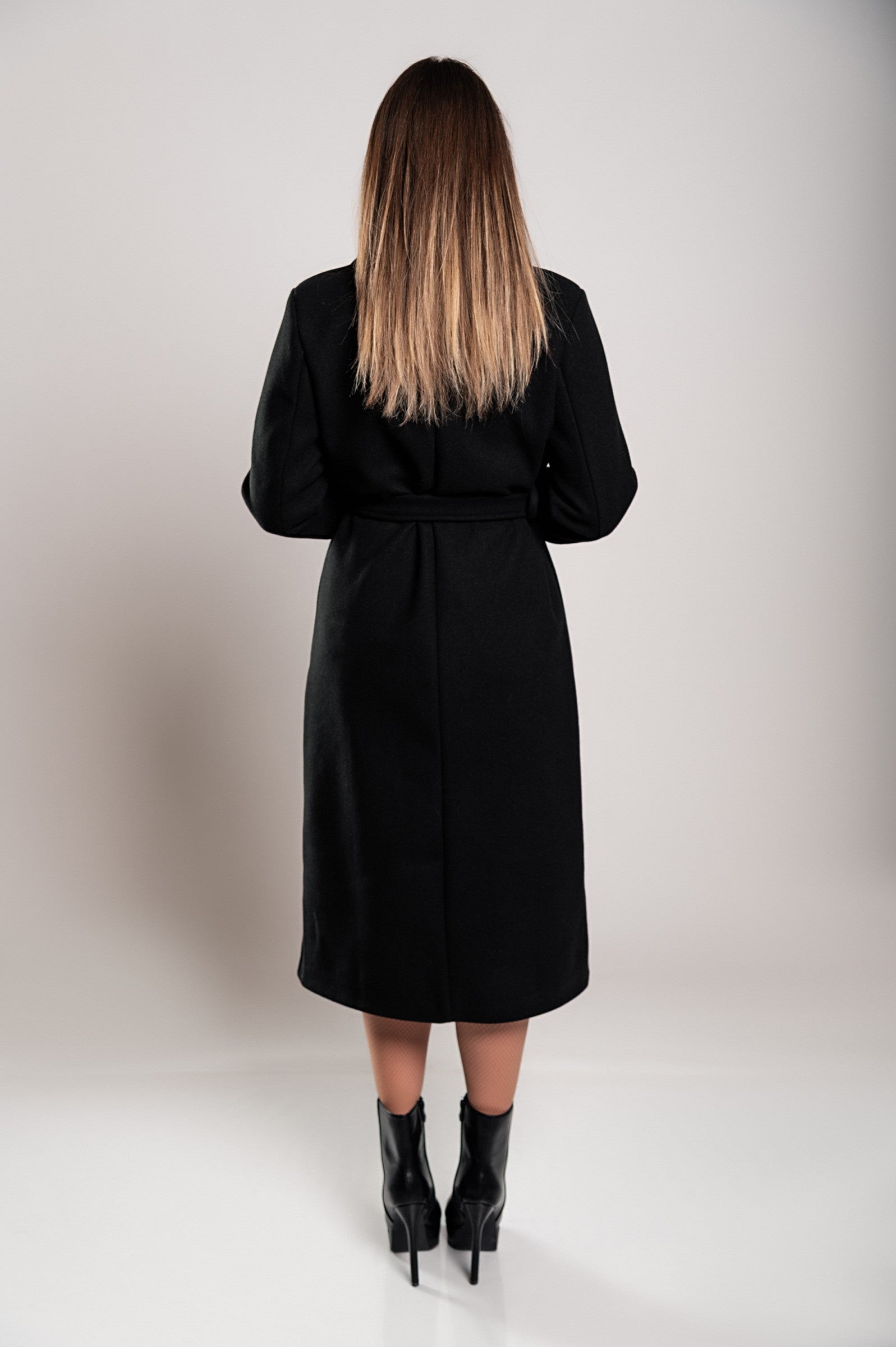 Elegant black long coat with buttons and decorative belt, showcasing classic collar and long sleeves.