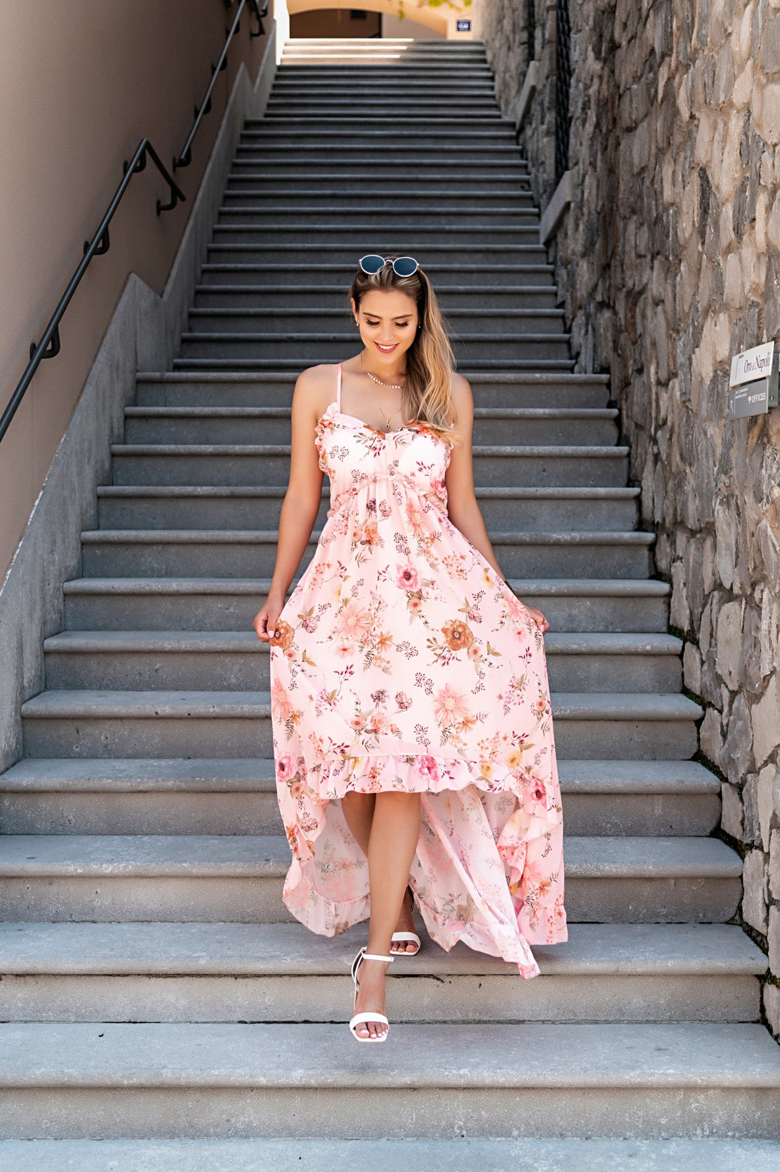 Elegant light pink maxi dress Noalla with print, featuring a plunging neckline, ruffle trim, and asymmetrical skirt with ruffles.